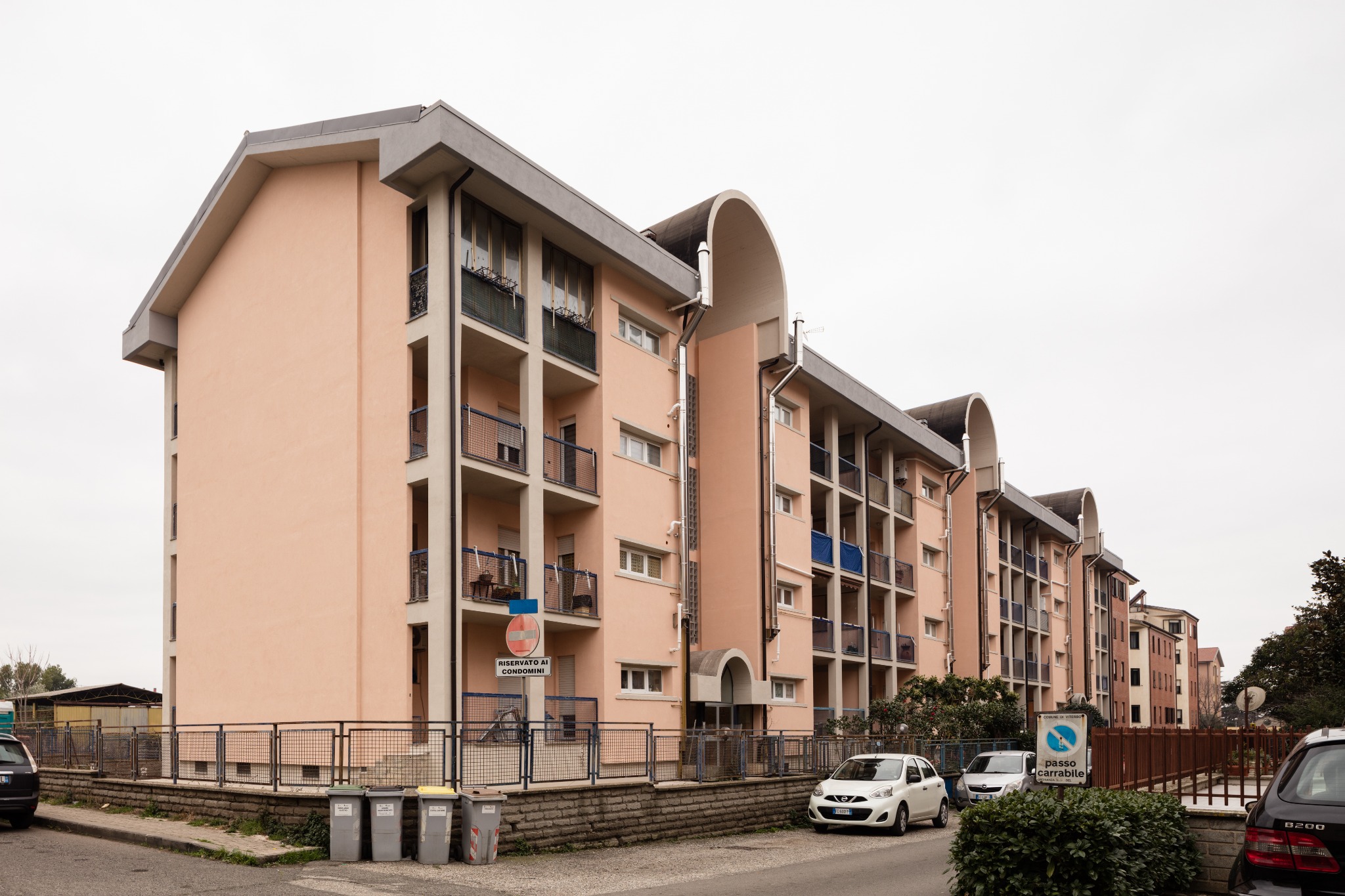 Prospetto del complesso residenziale con balconi e volumi curvi — intervento per ATER Viterbo